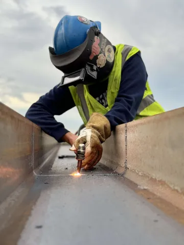 person wearing a helmet and gloves welding a piece of metal