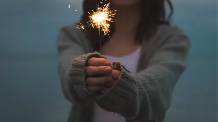 A woman holding a sparkler at dusk