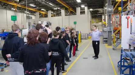 A group of individuals on a public tour of a manufacturing plant