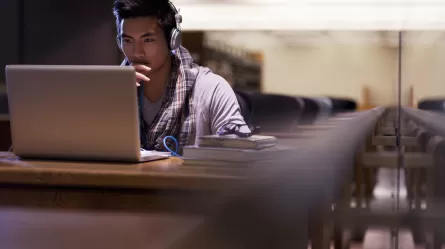 student at laptop in a library