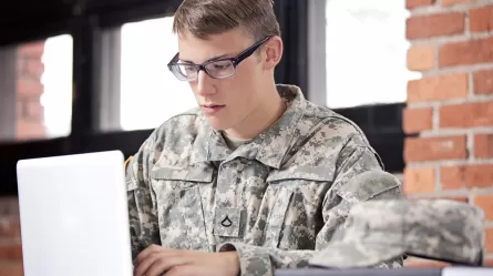 young man in military uniform on laptop