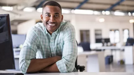 young man working at his laptop and smiling