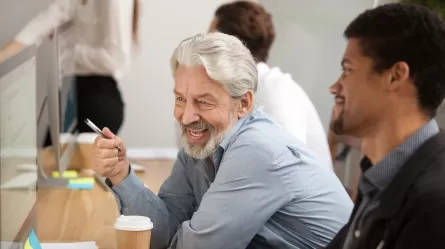 older man and younger man looking at computer screen in an offic
