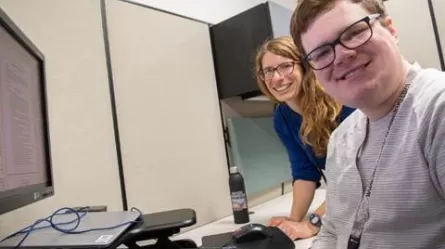 Photo of Katie and Colin at Colin's workstation at DEED