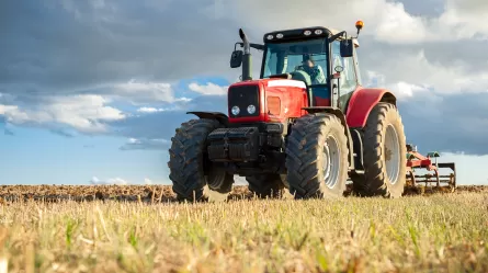 Large tractor plowing a field with worker driving on a sunny day.