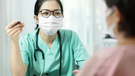 Registered Nurse talking with patient, both wearing masks