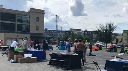 people in a parking lot with exhibitor tables in St. Paul