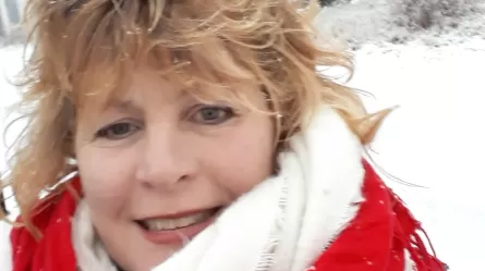 Smiling woman in winter clothes with snow in the background