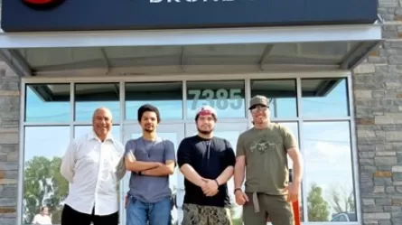 photo of four people standing in front of a business building
