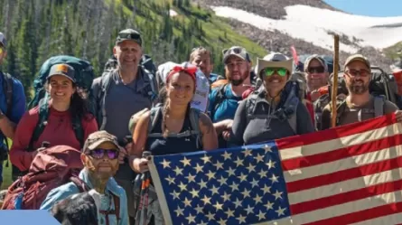 group of smiling people outdoors holding an American flag