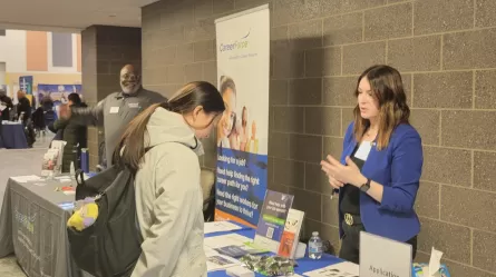 people talking at a display table with CareerForce information