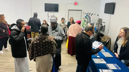 crowds of people talking with other people at display tables in a large room