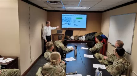 people in military uniform in a conference room looking at a person presenting workshop materials on screen