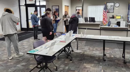 people in a room with a table and information desk style counter