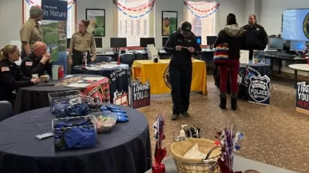 people sitting and standing at tables with materials for display arranged around perimeter of a large room