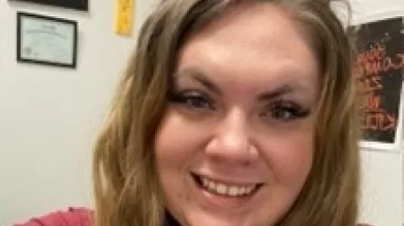 photo of Jenny, a smiling woman with long hair wearing a red shirt