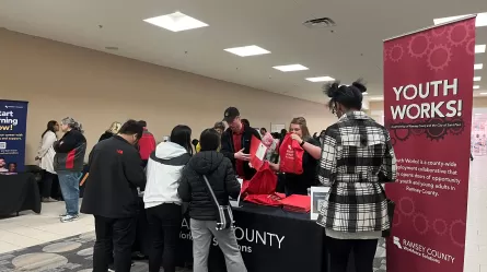 many people standing in a large room filled with tables with brochures and other resources