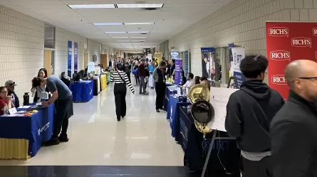 a long hallway lined with tables with many people standing and walking around