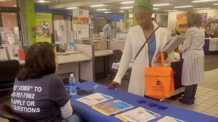 people standing and sitting at display tables with promotional materials on them