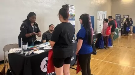 people standing and sitting at tables in a gymnasium