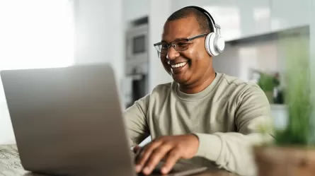 smiling person wearing headphones looking at laptop