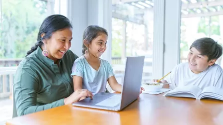 woman holding child looking at a laptop