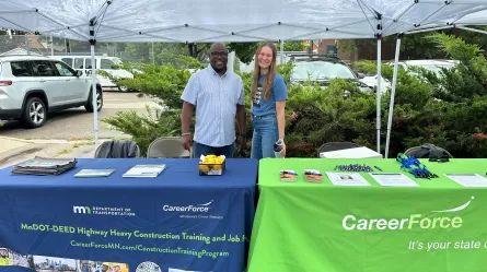 two people standing behind tables with table covers with CareerForce logo on them