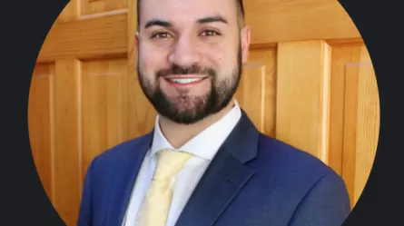smiling person wearing a shirt and suit jacket