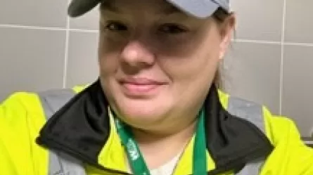 smiling person wearing baseball cap and reflective jacket