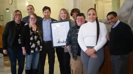 photo of nine people, one of the people is holding a framed certificate