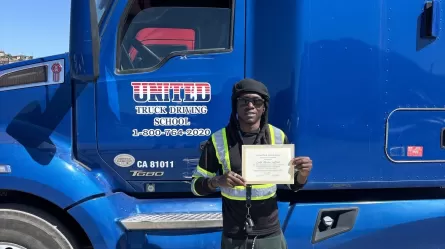 a person holding a certificate standing in front of a semi-truck 