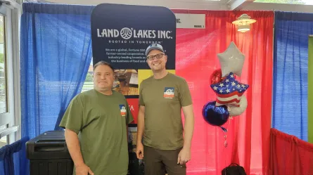 two people standing behind a table with a Land O' Lakes table skirt
