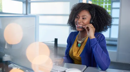 woman talking on headset sitting in front of a computer monitor