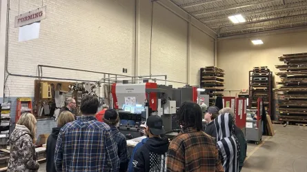 a group of people standing in a large room filled with mechanical equipment
