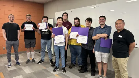photo of a large group of people standing in a room, some holding certificates