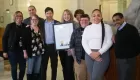 photo of nine people, one of the people is holding a framed certificate
