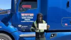 a person holding a certificate standing in front of a semi-truck 