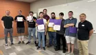 photo of a large group of people standing in a room, some holding certificates