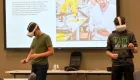 two people using virtual reality goggles in front of a screen with the words 'Southern Minnesota Tour of Manufacturing'