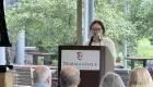 person speaking into a microphone, Normandale Community College logo on the lectern,Mue Hsae speaking at semiconductor manufacturing program graduation June 2025 