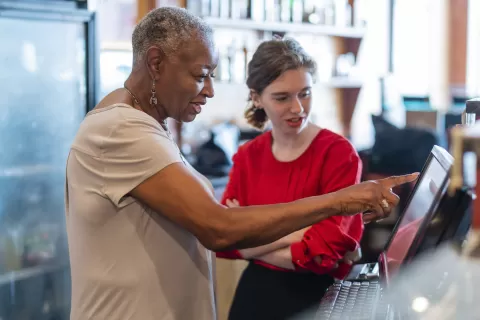 woman restaurant owner showing younger employee how to do something