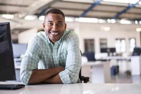 young man working at his laptop and smiling