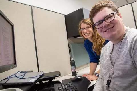 Photo of Katie and Colin at Colin's workstation at DEED