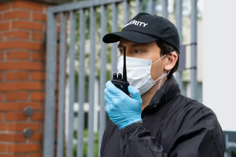 Security Guard in face mask talking on walkie talkie.