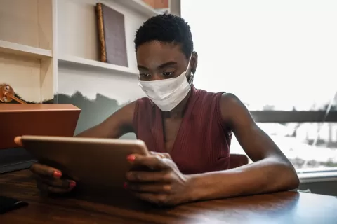 woman in mask using laptop