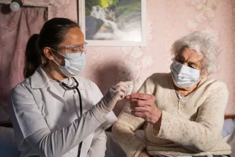 Nursing assistant and patient, both wearing masks