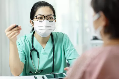 Registered Nurse talking with patient, both wearing masks