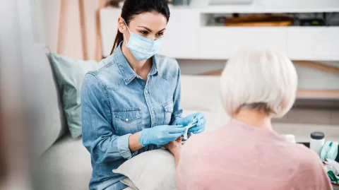 Healthcare worker wearing a face mask and gloves working with a patient in a home