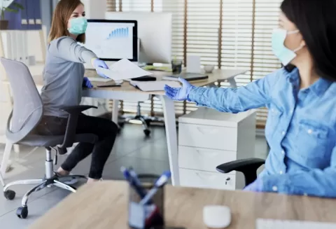 two women in an office setting, both women wearing masks