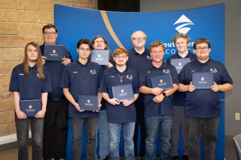nine young people holding certificates of graduation